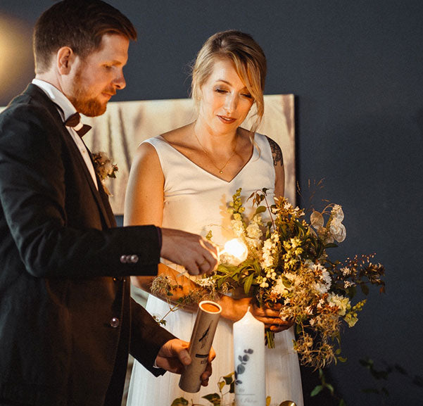 Moderne Hochzeitskerze wird von Hochzeitspaar angezündet