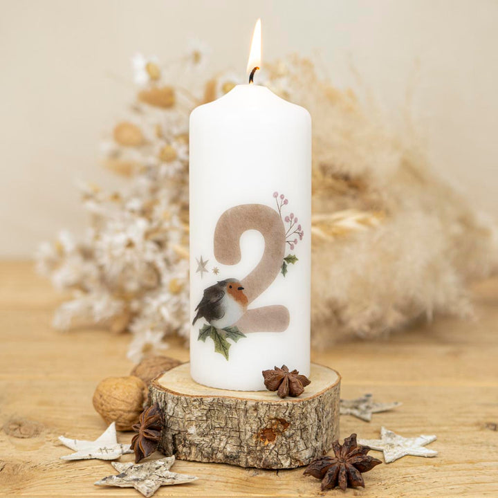Kerze für den Advent mit einem Rotkehlchen das auf der Nummer Zwei und einem Zweig sitzt