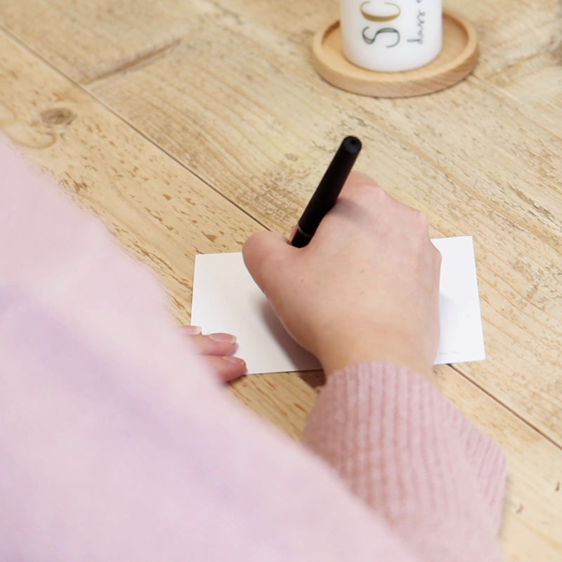Grußkarte wird handschriftlich mit Geburtstagswünschen beschriftet