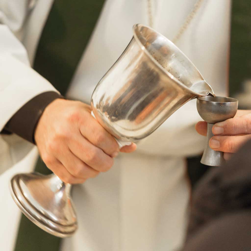 Pastor mit einem Kelch in der Hand