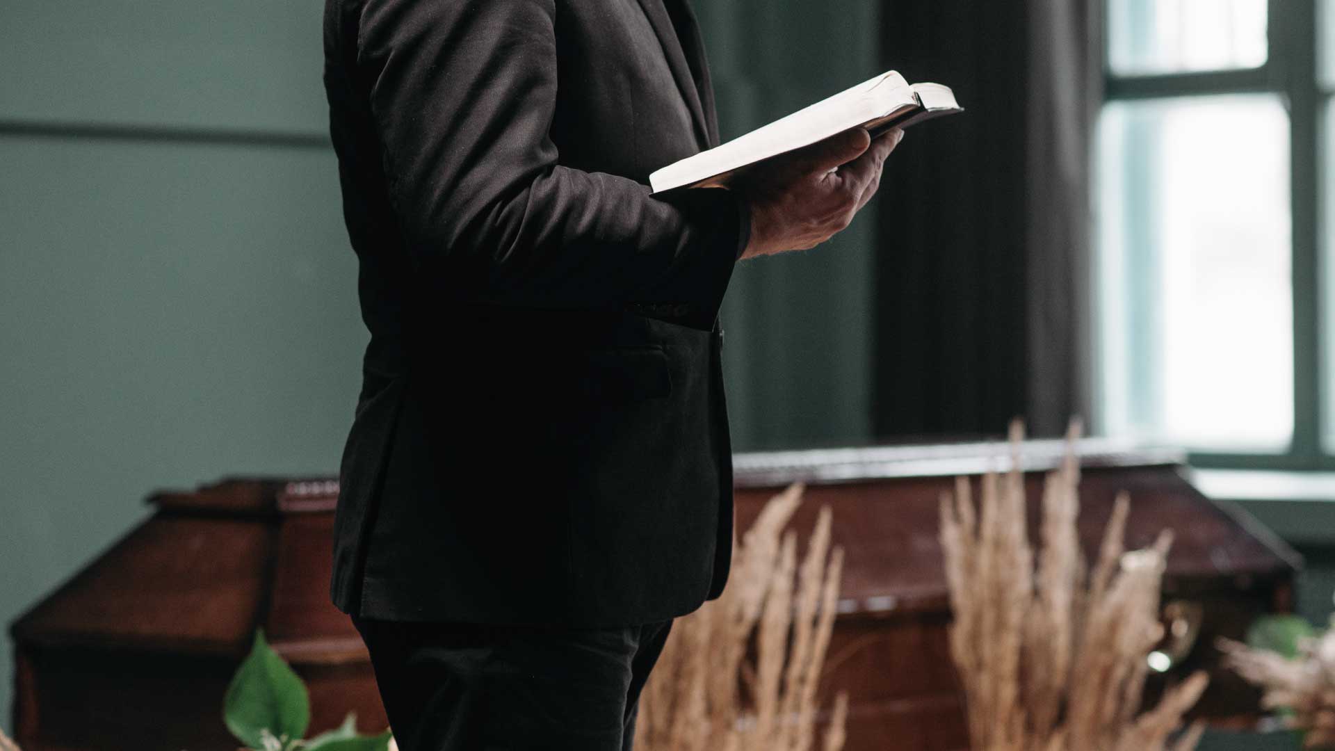 Pastor mit Buch auf der Beerdigung