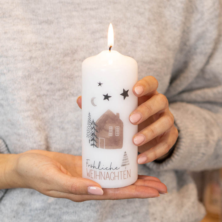 Frau hält Weihnachtskerze mit dem Aufdruck Fröhliche Weihnachten