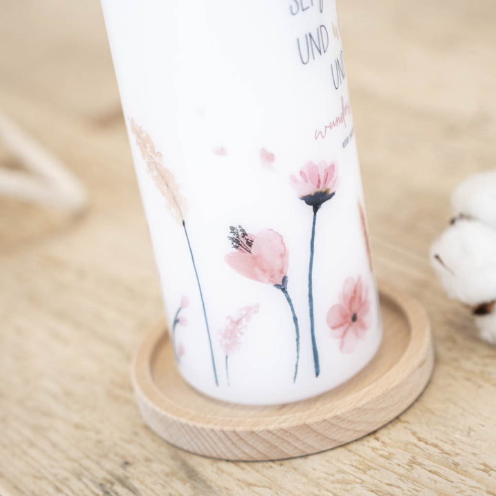 Taufkerze Blumen Sophie steht auf einem Kerzenhalter aus Holz